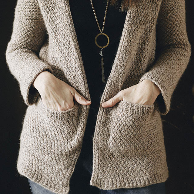 Image of my hands in pickets of my Kapsel cardigan knit in Paton's classic natural mix.