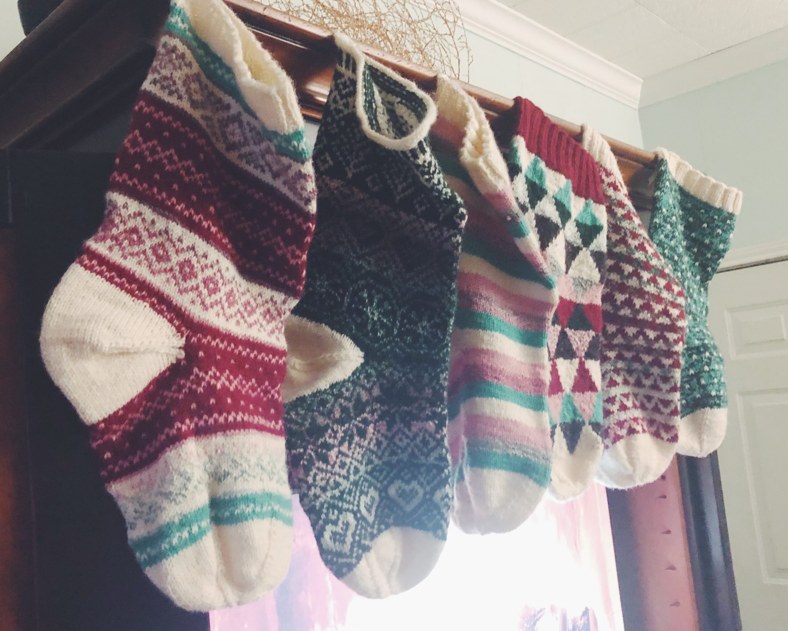 Image of my hand knit Christmas stockings hanging with care in front of our TV with a fireplace screen saver playing.