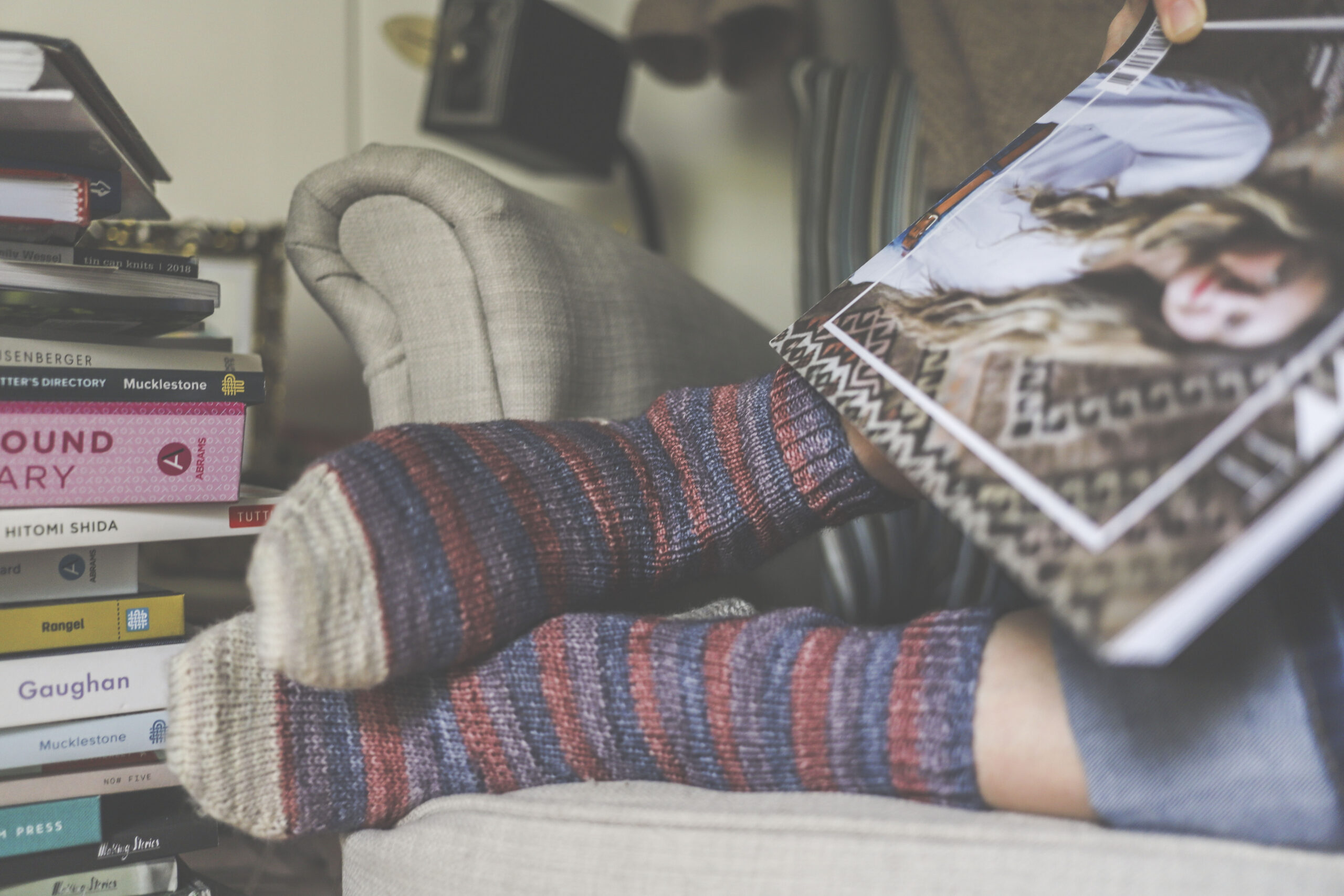 Image of me curled up reading an issue of Knit Wit wearing my socks knit in the Michelle colorway from Lovebird Lane