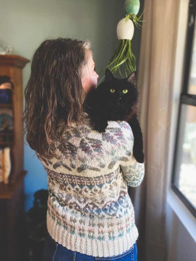 Image of me holding a very bad kitty on my shoulder while I wear the Guthrie color work yoke sweater pattern.