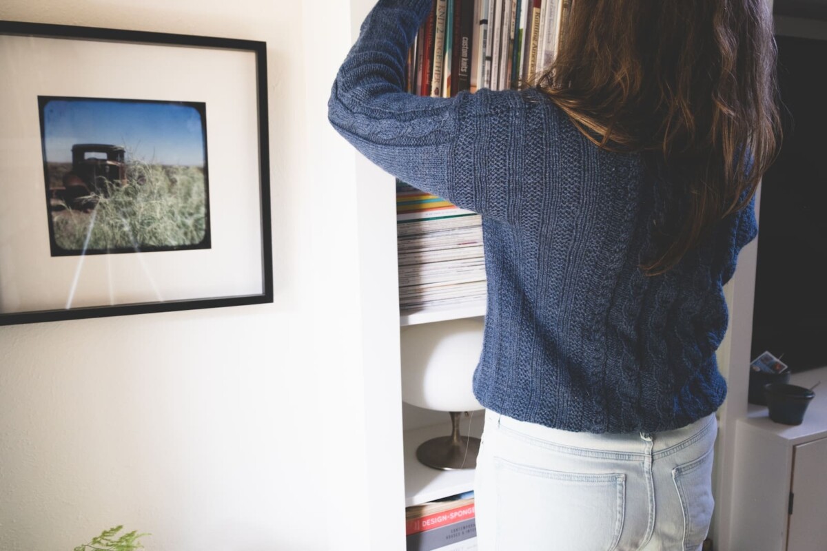 Image of me pretending to look for a book in the bookshelf to show the back of my Lately sweater.