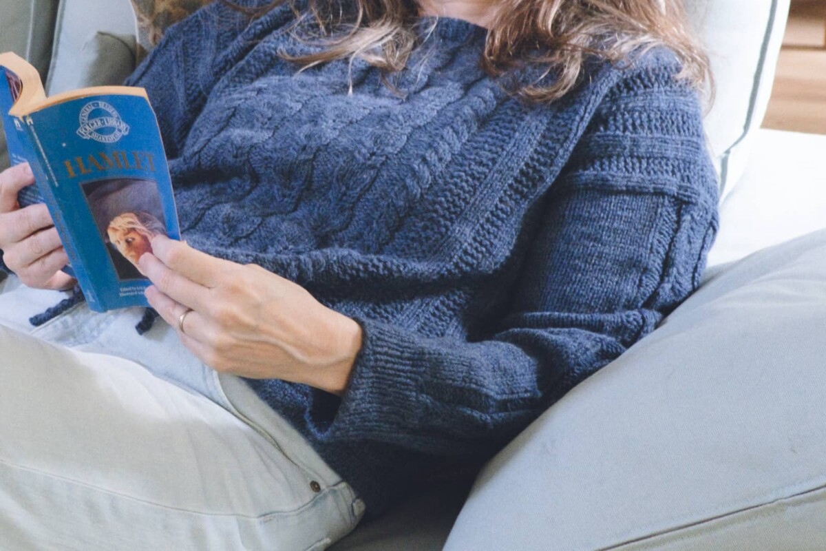 Image of me pretending to read on the couch all snuggled up in the Lately Pullover.