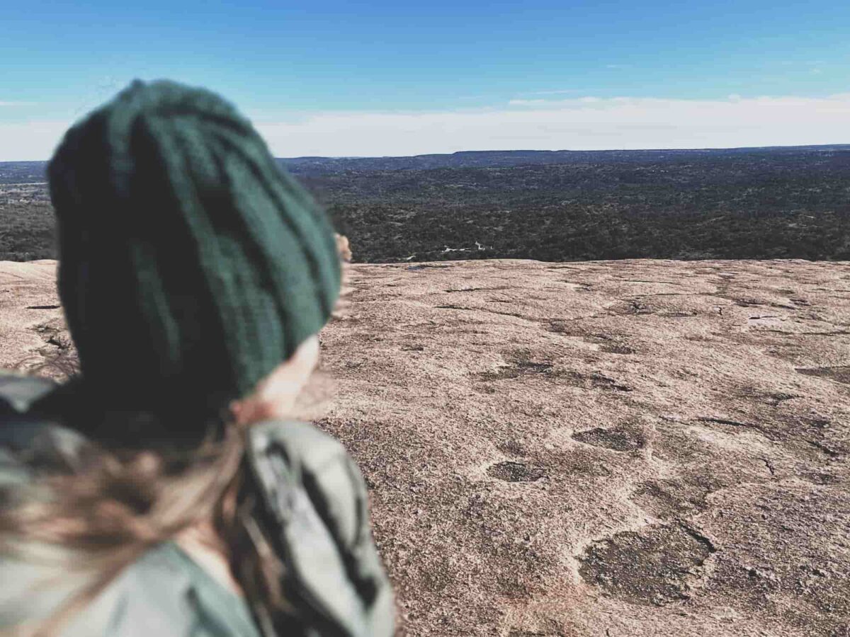 Image of me wearing my Axial knitted hat on top of Enchanted Rock in my I Turned 50 Hike.